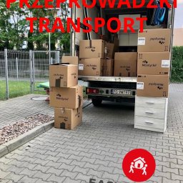 Easy Movers - Częściowo załadowany samochód dostawczy z kartonami firmy Mölnlycke i białą komodą na chodniku przed budynkiem.