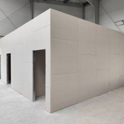 Everest - Wnętrze magazynu z wydzielonymi pomieszczeniami z płyt gipsowo-kartonowych, widoczne metalowe profile ościeżnic drzwiowych i surowa betonowa posadzka.