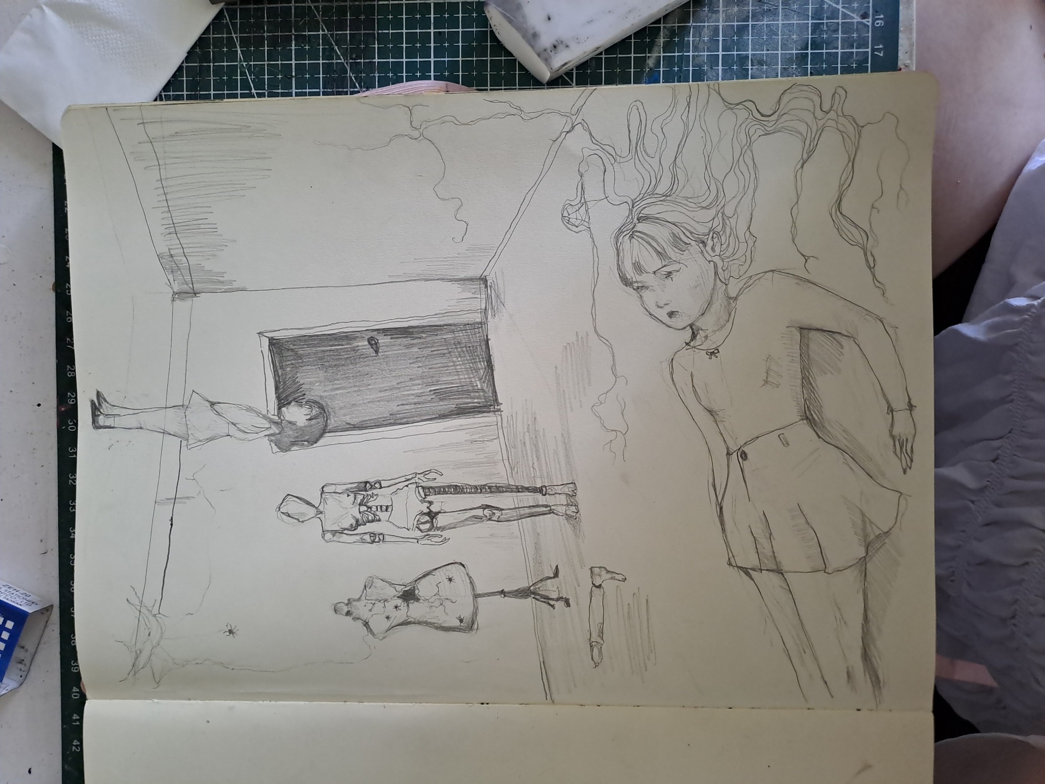 Szkic ołówkiem w otwartym notatniku przedstawiający dziewczynę, manekina, szkielet i postać leżącą w pokoju, z pajęczyną w rogu.