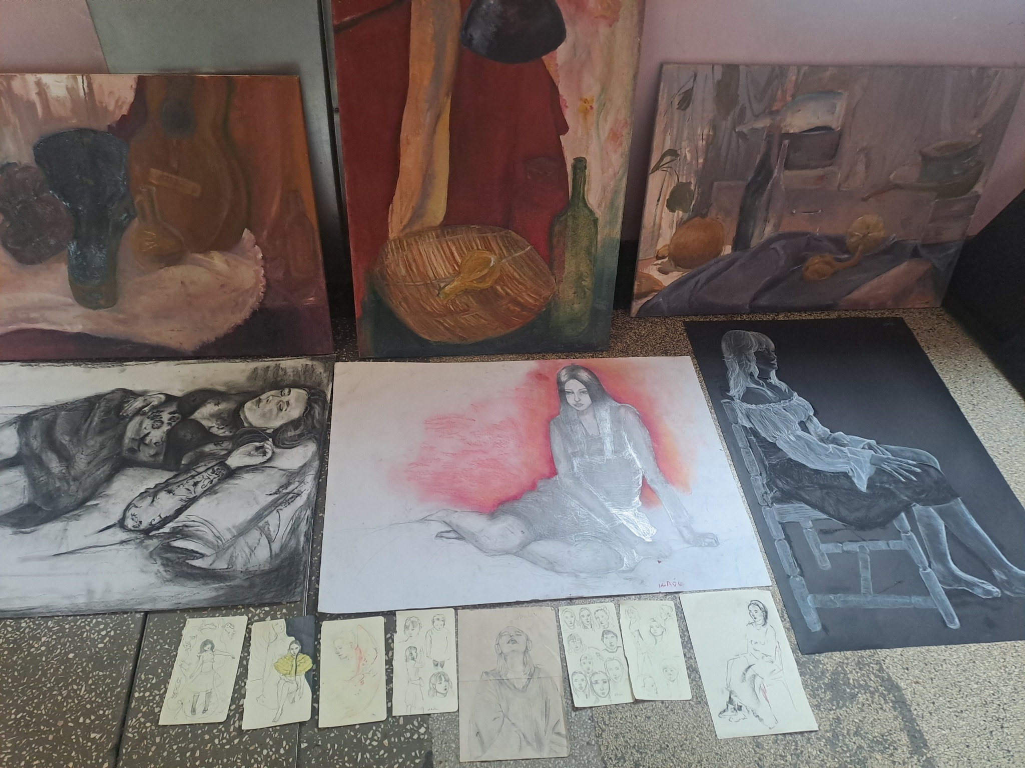 Zestaw obrazów i szkiców o różnej tematyce: martwa natura, portrety, akty, wykonane w technice olejnej i ołówkiem, ułożone na podłodze.