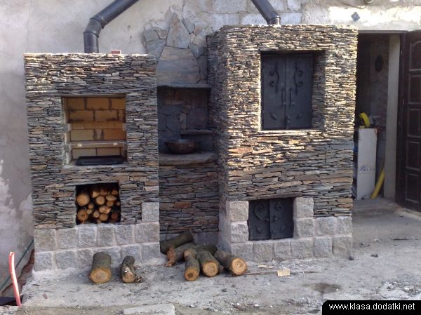 Ogródek z kamiennym grillem i piecem chlebowym, z miejscem na drewno i z kutymi drzwiczkami, wykończony drobnymi płytkami kamiennymi.