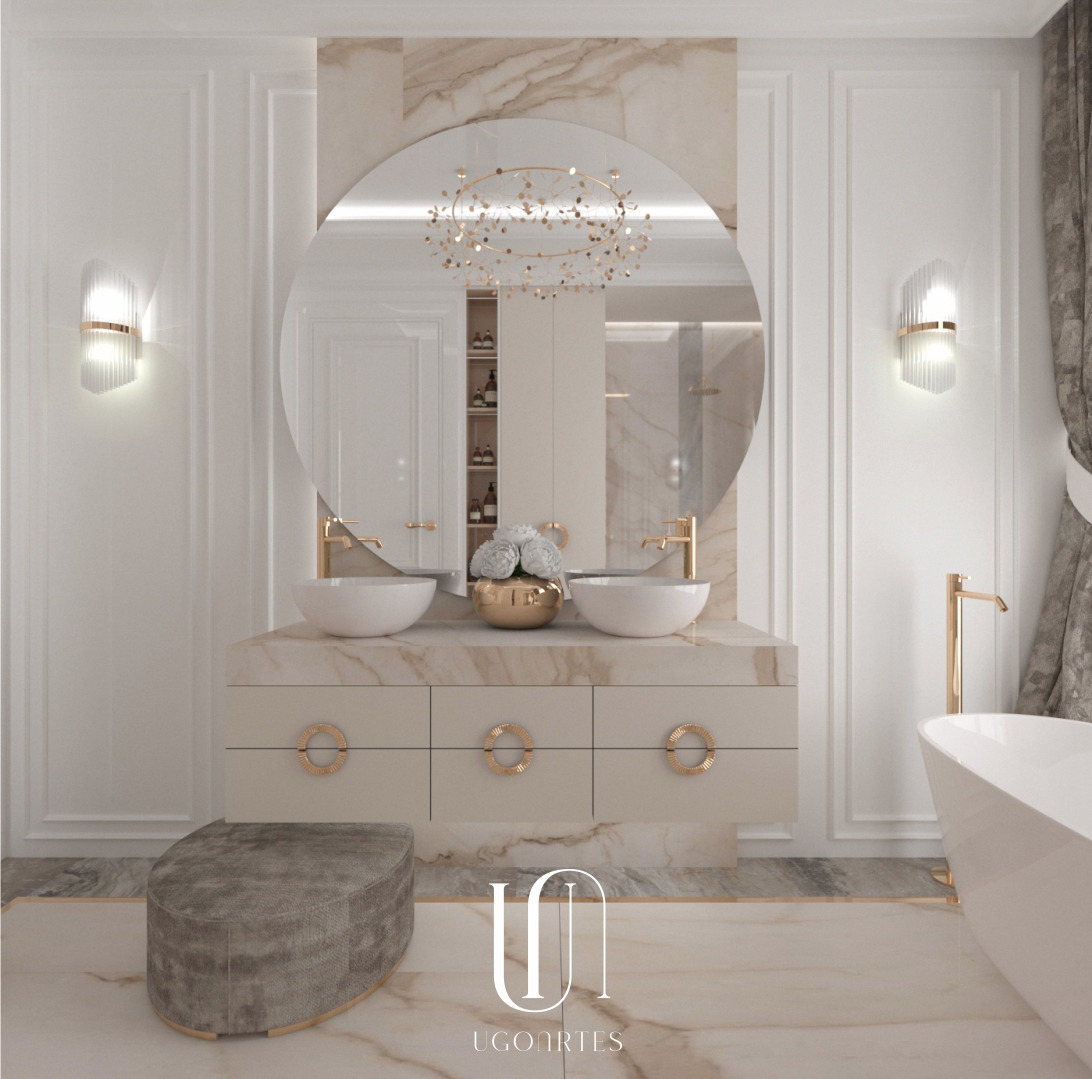 Elegancka łazienka z marmurowym wykończeniem, podwójna umywalka z złotymi bateriami, okrągłe lustro z ozdobnym oświetleniem, pufa i wanna wolnostojąca.