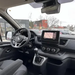 Wnętrze nowoczesnego busa Renault z nawigacją GPS na desce rozdzielczej, widok z perspektywy kierowcy.