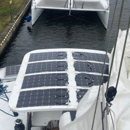 Ru-Bud - Widok z góry na jacht z panelami słonecznymi na pokładzie, zacumowany w porcie. W tle widoczny drugi jacht.