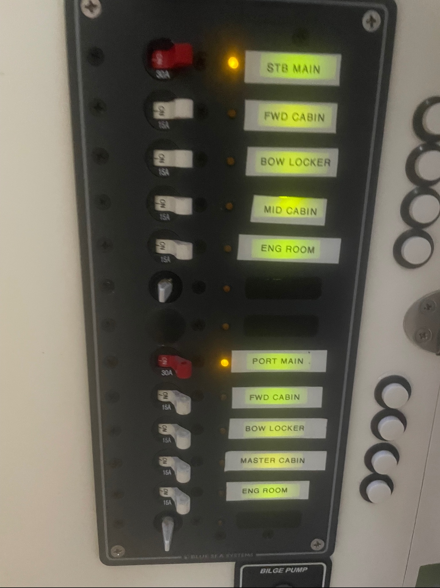 Panel elektryczny z bezpiecznikami i przełącznikami oznaczonymi nazwami obwodów, niektóre z nich podświetlone. Widoczne oznaczenia amperażu i nazwy obwodów.