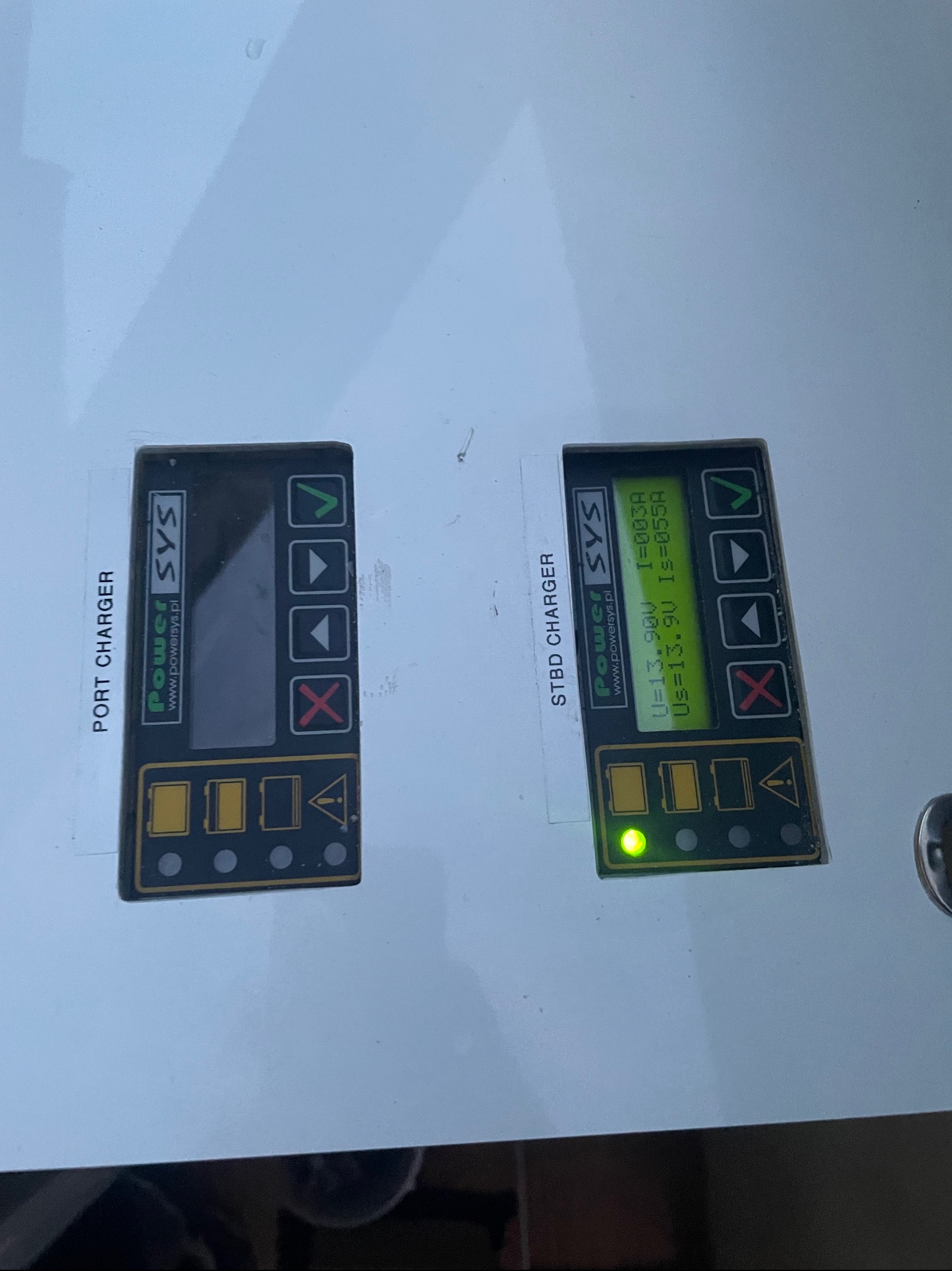 Panel sterowania ładowarkami Power SYS: Port Charger z wygaszonym ekranem i Stbd Charger z aktywnym wyświetlaczem pokazującym parametry ładowania.