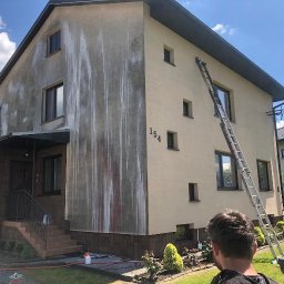 Profesjonalne czyszczenie elewacji budynków, dachów oraz kostki brukowej, Mateusz Leniar - Dwukondygnacyjny dom z częściowo umytą elewacją, widoczne zacieki po czyszczeniu, drabina oparta o ścianę, numer domu 154.