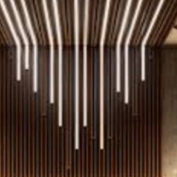 Baubudowa - Nowoczesny design wnętrza: drewniana ściana z pionowymi paskami oświetlenia LED, wiszące lampy kuliste po bokach.