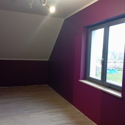 GRZECH-BUD Grzegorz Ludwiczak - Pokój na poddaszu po malowaniu ścian na kolor burgundowy, z jasną podłogą z paneli i oknem z widokiem na ogród.