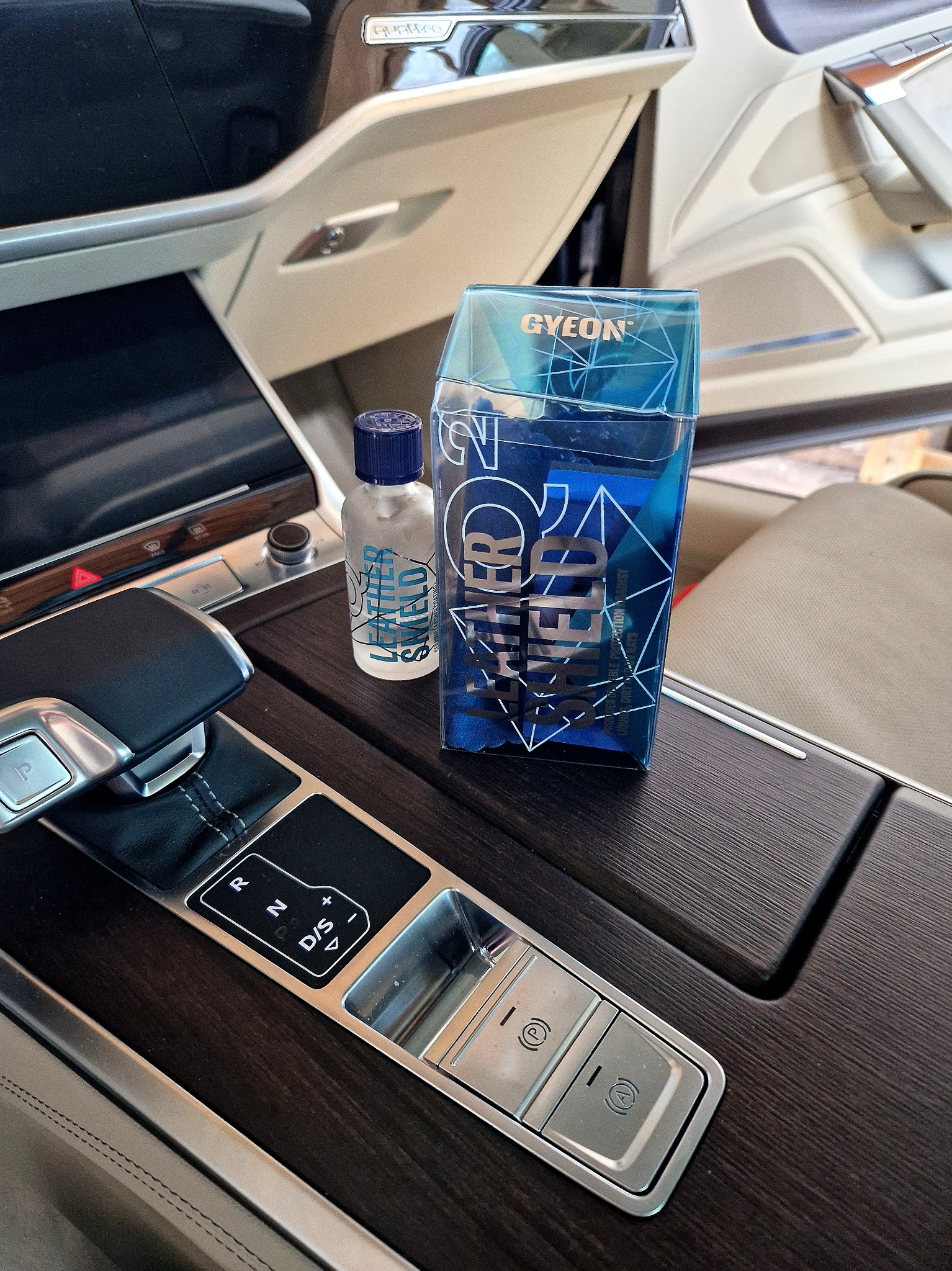 Środek do czyszczenia i ochrony skórzanej tapicerki samochodowej marki Gyeon, umieszczony na konsoli środkowej luksusowego auta.