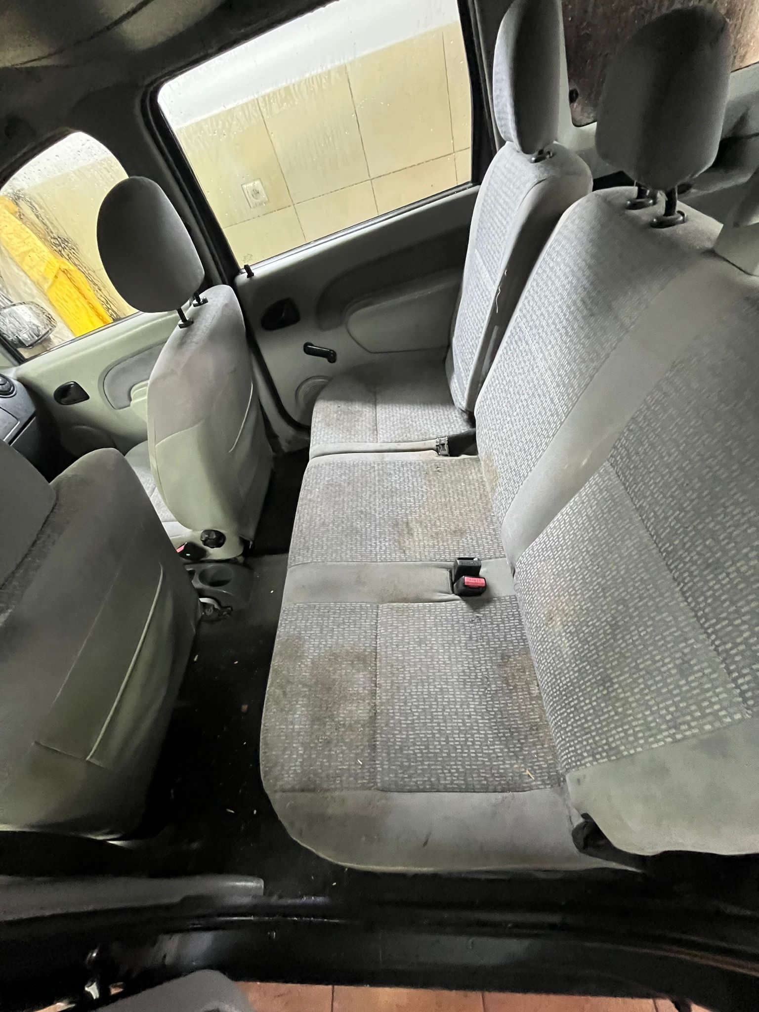 Wnętrze samochodu z widocznymi, mocno zabrudzonymi tapicerowanymi siedzeniami, wymagającymi profesjonalnego prania