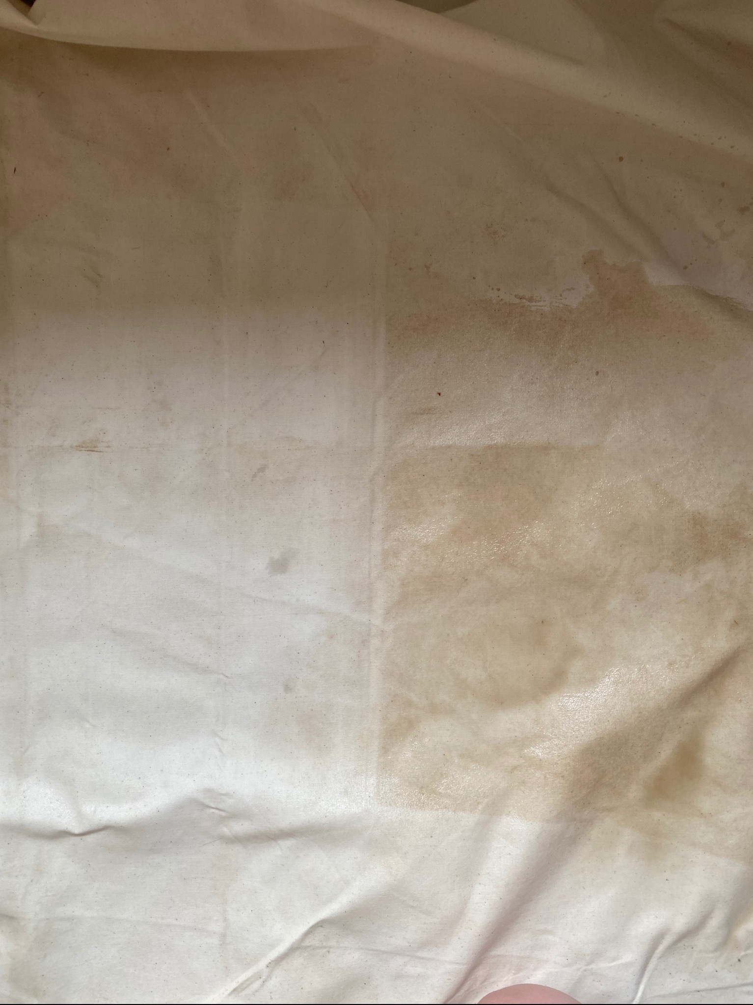 Fragment tkaniny z widocznym efektem czyszczenia; lewa strona jaśniejsza, prawa strona z zabrudzeniami.