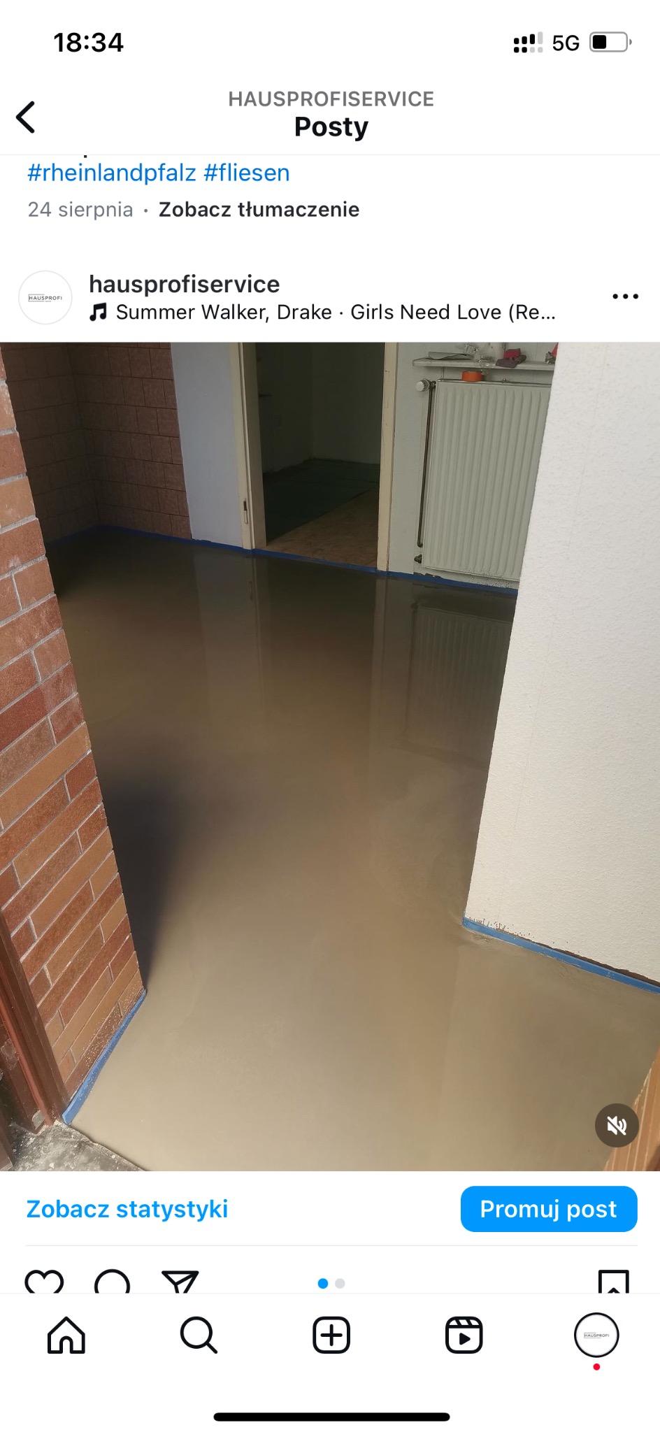 Świeżo wylana, samopoziomująca wylewka podłogowa w pomieszczeniu z ceglaną ścianą i grzejnikiem, zabezpieczona taśmą malarską przy ścianach.