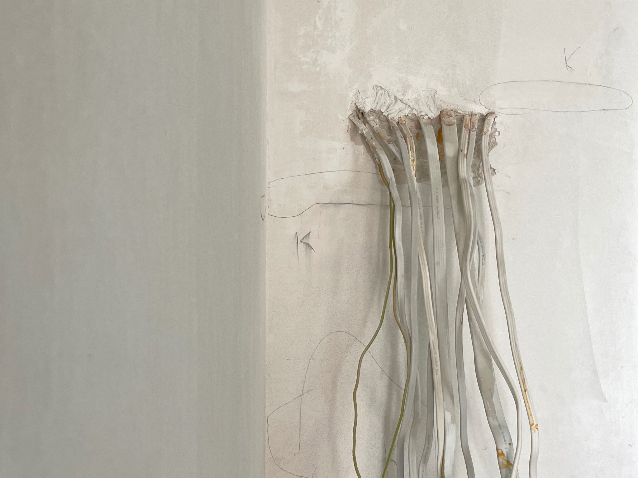 Instalacja elektryczna w ścianie: wystające kable z puszki, surowy stan, widoczne ślady po kuciu, przygotowanie do dalszych prac wykończeniowych.