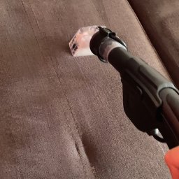 Pranie Tapicerki, konserwacja skór czyszczenie parowe, ozonowanie - Czyszczenie brązowej kanapy za pomocą odkurzacza piorącego z przezroczystą końcówką, widoczna różnica w kolorze po czyszczeniu.