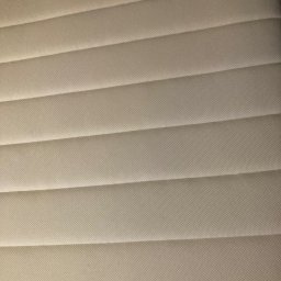 Pranie Tapicerki, konserwacja skór czyszczenie parowe, ozonowanie - Jasny materac z wyraźnymi, poziomymi przeszyciami, ukazujący fakturę tkaniny. Delikatne cieniowanie podkreśla detale.