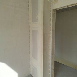 CatHouse - Montaż płyt karton-gips na ścianie, widoczne profile i łączenia. Świeże, surowe wykończenie wnętrza w trakcie prac. Fragment instalacji elektrycznej przy futrynie.