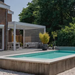 Nowoczesny taras z basenem, obok domu z cegły. Biała pergola z poziomymi lamelami nad strefą relaksu. Donice z roślinami i jasne kamyki dekoracyjne.