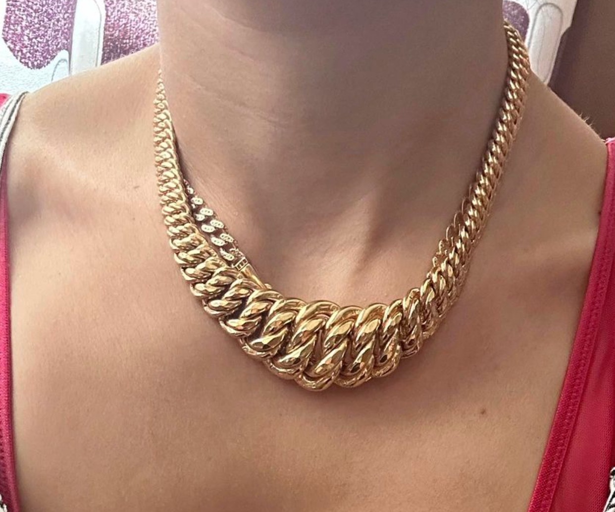 Kobieta z grubym, złotym łańcuchem na szyi, widoczne detale splotu i zapięcie.