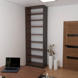 MEBLEZPACZKI.PL PROSTA SPÓŁKA AKCYJNA - Wysoki regał z ciemnego drewna z półkami, laptop na biurku, drewniane drzwi z czarnymi wstawkami, wazon z dekoracją roślinną. Aranżacja wnętrza w neutralnych barwach.