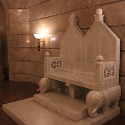 Jakub Bak - Monumentalna marmurowa ławka z motywem słoni w klasycznym wnętrzu z marmurowymi ścianami i wazą w tle.