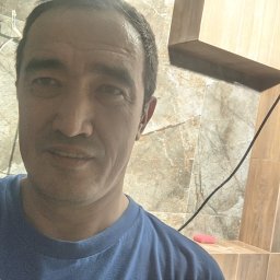 Volodymyr Tsoi - Autoportret glazurnika na tle częściowo wykończonej łazienki z marmurowymi i drewnopodobnymi płytkami, widoczne przewody elektryczne.