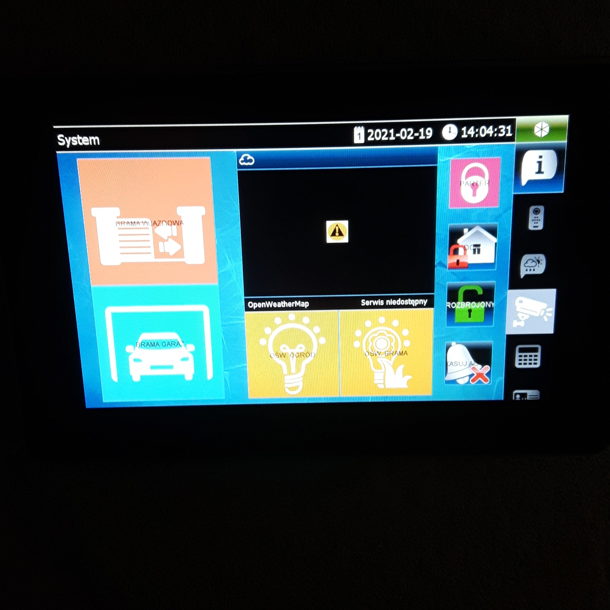 Ekran panelu sterowania systemu inteligentnego domu, wyświetlający ikony sterowania bramą wjazdową, bramą garażową, oświetleniem ogrodu, oświetleniem bramy, stan alarmu oraz monitoringiem. Data...