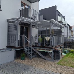 USŁUGI OGÓLNOBUDOWLANE Łukasz Lieske - Nowoczesny taras z zadaszeniem i metalowymi schodami, szara kolorystyka, widok z poziomu gruntu. Elementy konstrukcyjne z metalu.