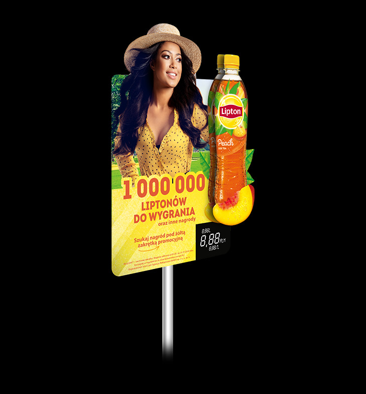Reklama napoju Lipton Peach na displayu z wizerunkiem uśmiechniętej kobiety w kapeluszu i informacją o promocji '1 000 000 Liptonów do wygrania'.