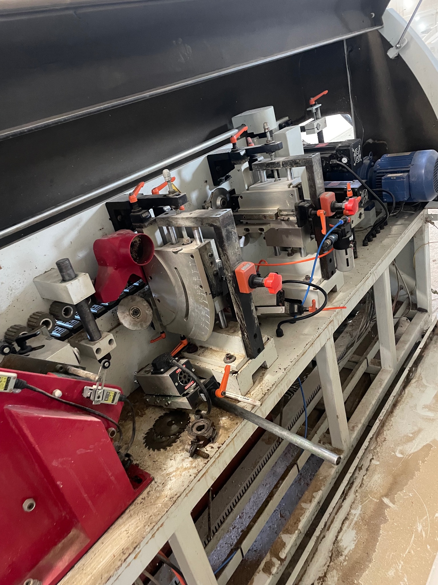 Wielogłowicowa frezarka do drewna z elementami pneumatyki, widoczne ślady użytkowania i drobne zabrudzenia na stole roboczym.