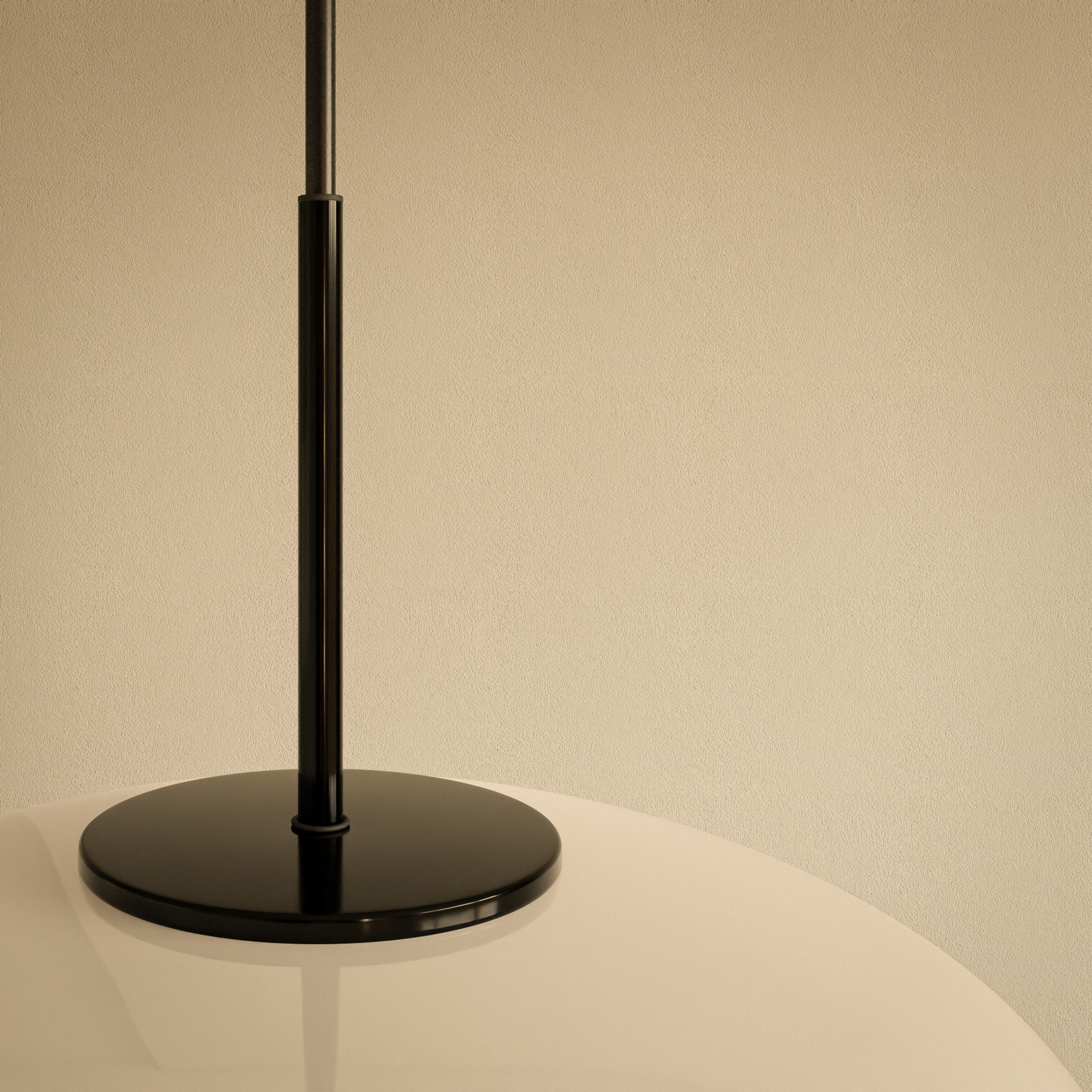 Minimalistyczna lampa podłogowa z czarną podstawą i białym kloszem na tle beżowej ściany o delikatnej fakturze.