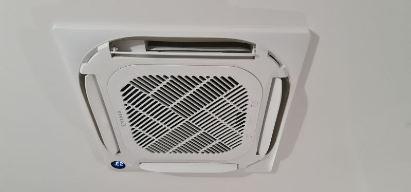 Biała, sufitowa jednostka klimatyzacyjna Rotenso z widocznym wyświetlaczem temperatury 23 stopnie Celsjusza.