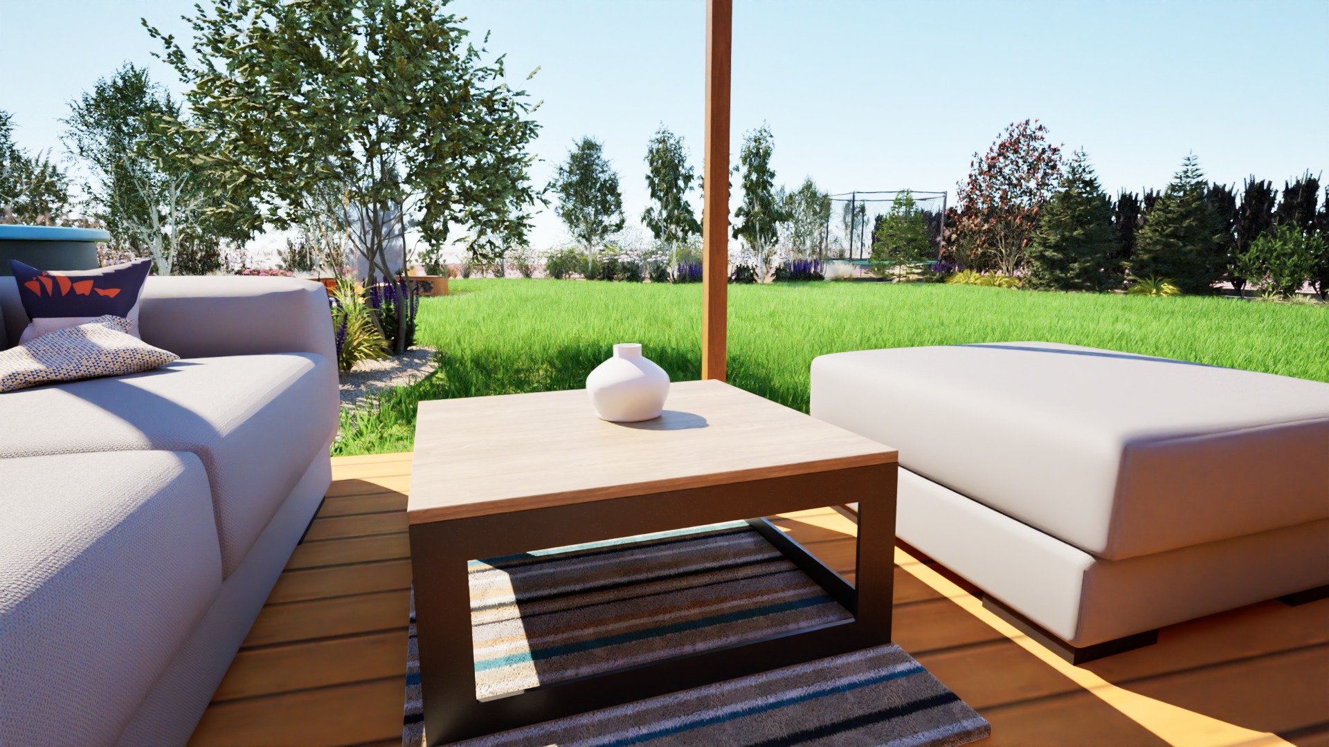 Aranżacja tarasu z jasnoszarą sofą, pufem i stolikiem kawowym z białą wazą na tle zadbanego trawnika i zieleni.