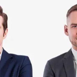 Portret dwóch prawników w garniturach na jasnym tle, jeden z włosami zaczesanymi do góry, drugi z krótką brodą i wzorzystym krawatem.