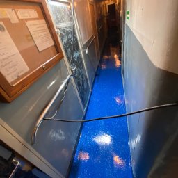 Vanguard Marine - Wnętrze korytarza z błyszczącą, niebieską podłogą z efektem brokatu, szare ściany i metalowe elementy wykończeniowe.