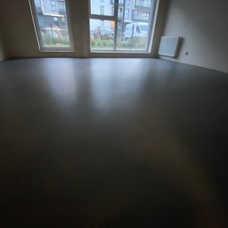 Vanguard Marine - Wnętrze pokoju z nową, ciemną, błyszczącą podłogą, widok na okna z budynkami na zewnątrz.