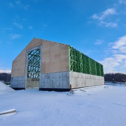 JK HAUS-WIĄZAR-SYSTEM SPÓŁKA Z OGRANICZONĄ ODPOWIEDZIALNOŚCIĄ - Surowy stan budynku z elementami konstrukcji szkieletowej na fundamencie betonowym, pokryty śniegiem w zimowy dzień.