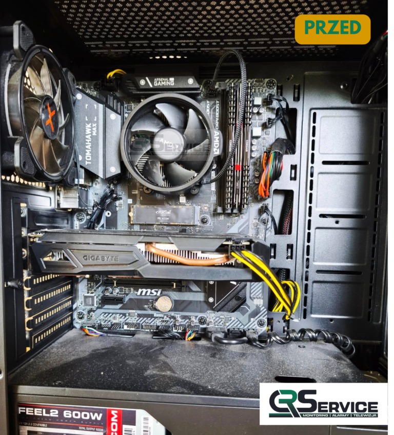 Wnętrze brudnej obudowy komputera stacjonarnego przed czyszczeniem lub naprawą. Widoczne komponenty: płyta główna, karta graficzna Gigabyte i MSI, chłodzenie procesora AMD.