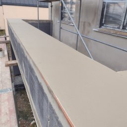 Paweł Dworakowski - Świeżo otynkowana elewacja balkonu z widocznymi rusztowaniami i zabezpieczonymi oknami folią.