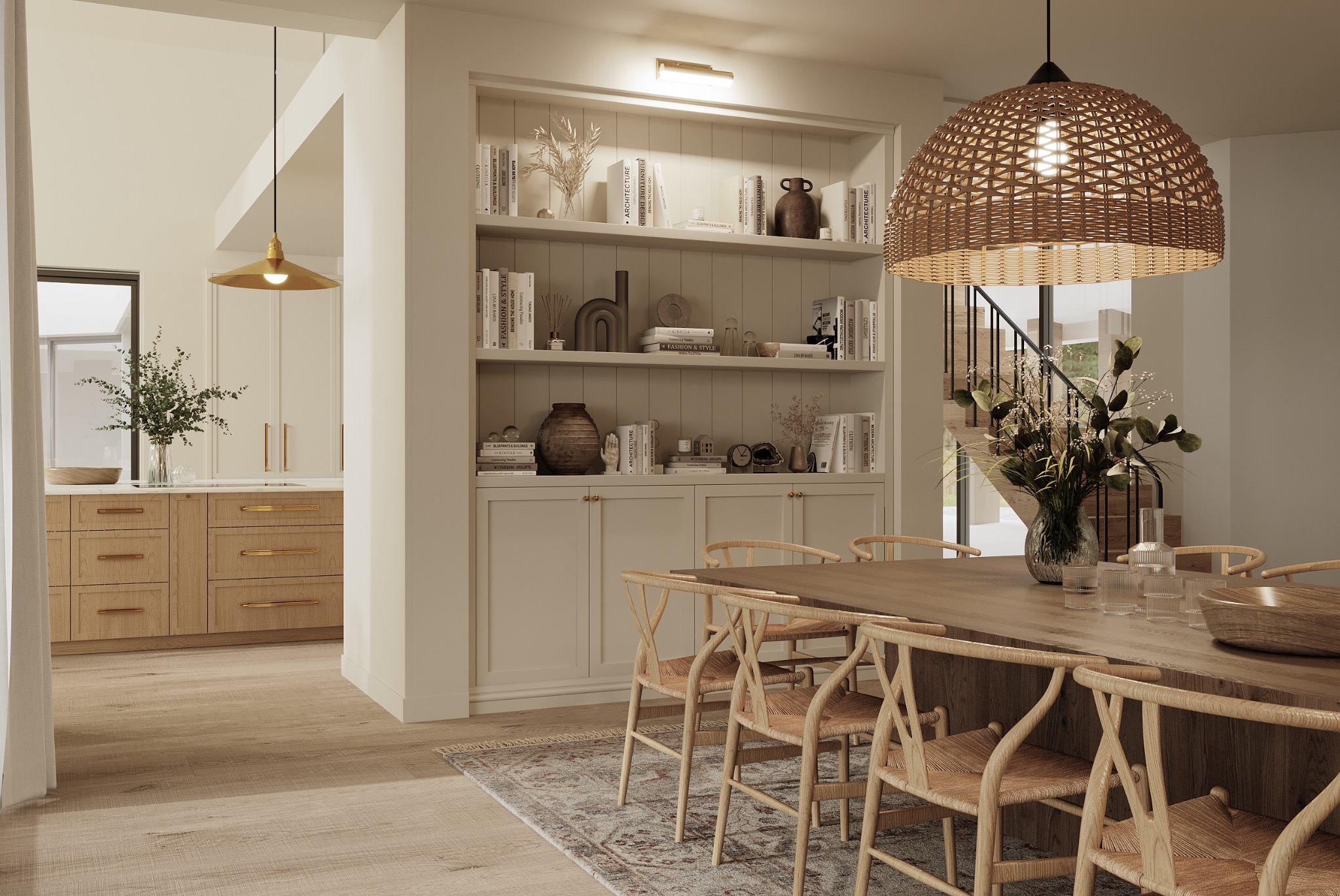 Jasne wnętrze jadalni z drewnianym stołem, krzesłami z wikliny, dywanem w orientalny wzór i regałem z książkami. W tle widoczna kuchnia z drewnianymi szafkami i złotymi uchwytami oraz schody.