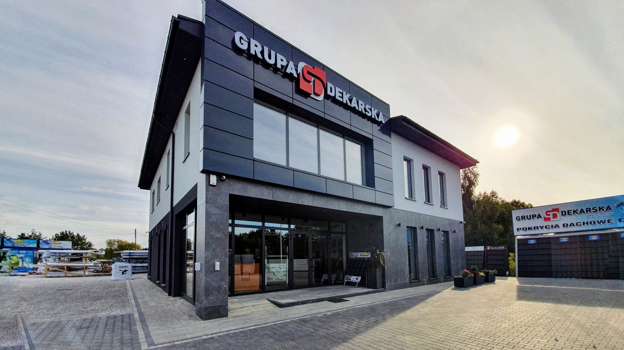 Nowoczesny budynek firmy dekarskiej z dużym logo 'Grupa Dekarska' na elewacji, prezentacja materiałów dachowych na zewnątrz.