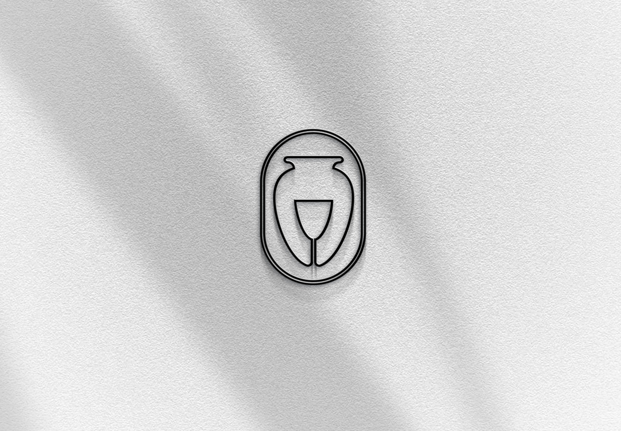 Minimalistyczny, czarno-biały logotyp przedstawiający wazon i kieliszek do wina, umieszczony w owalnej ramce na białym, teksturowanym tle z subtelnymi cieniami.
