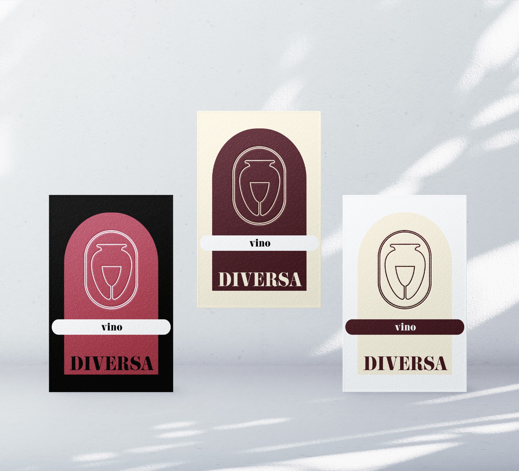 Trzy warianty wizytówki z logo i napisem 'vino DIVERSA' na tle białej ściany z cieniem liści.