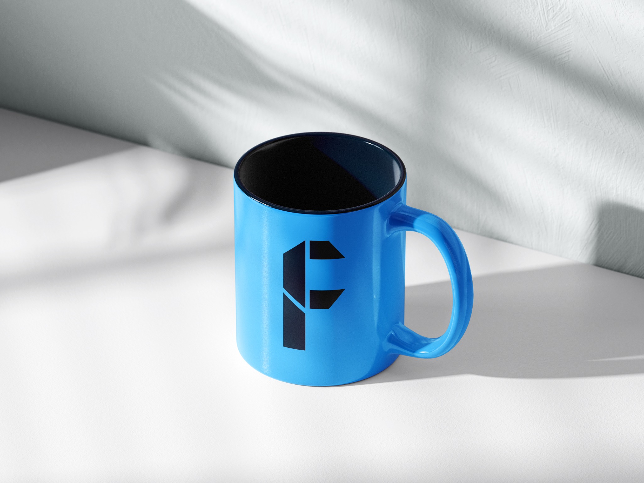 Błękitny kubek z czarnym wnętrzem i czarnym geometrycznym logo litery F, ustawiony na białym tle z miękkimi cieniami.