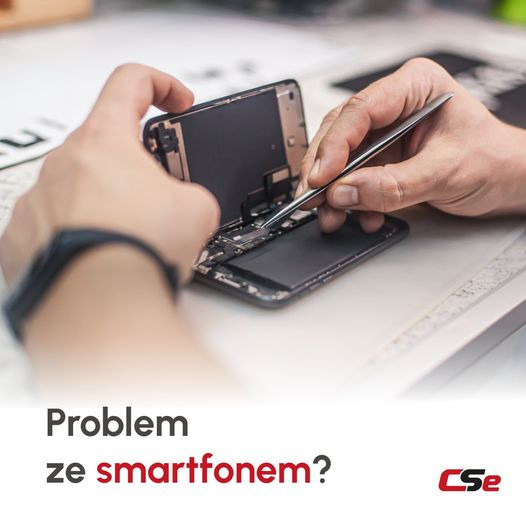 Rozłożony smartfon na białym stole, naprawiany precyzyjnymi pęsetami, widoczny zegarek na nadgarstku serwisanta.