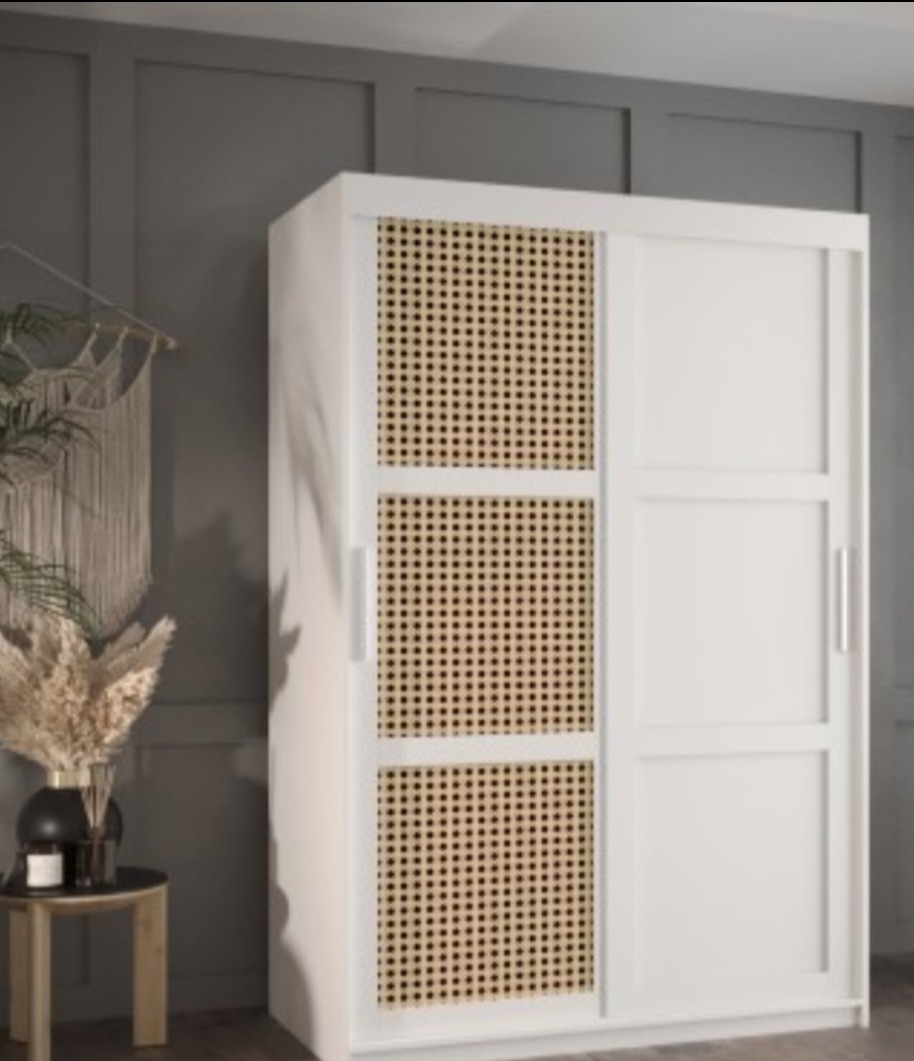 Biała szafa przesuwna z trzema panelami z plecionki rattanowej na jednych drzwiach, stojąca w pokoju z szarymi ścianami i dekoracjami w stylu boho.