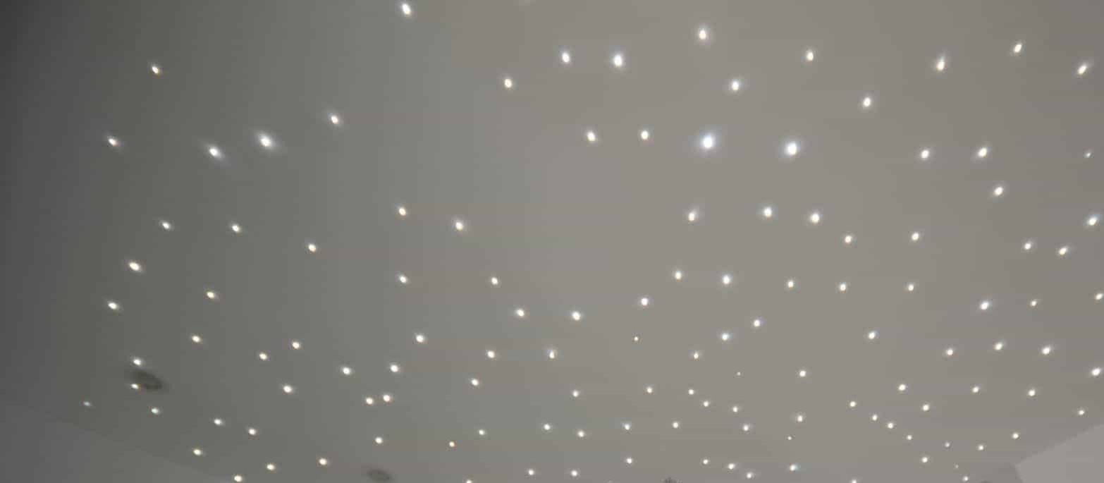 Biały sufit z równomiernie rozmieszczonymi punktowymi lampkami LED tworzącymi efekt gwiaździstego nieba, wykonany w domu w Sierakowicach.