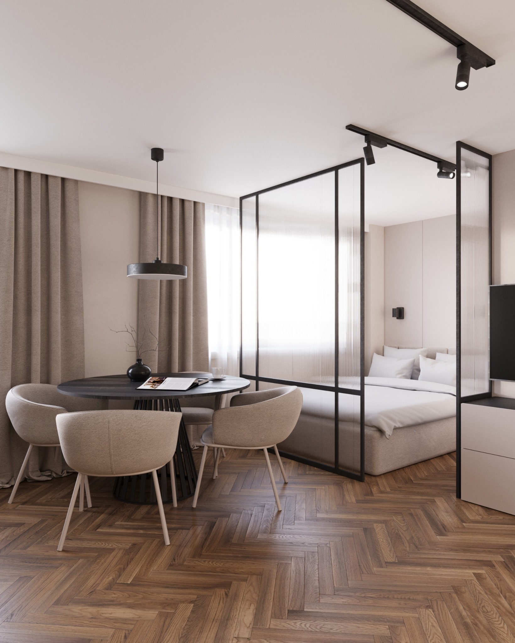 Wnętrze mieszkania z wydzieloną strefą sypialnianą za pomocą szklanej ścianki działowej; widoczny okrągły stół z krzesłami, lampa wisząca i parkiet w jodełkę.