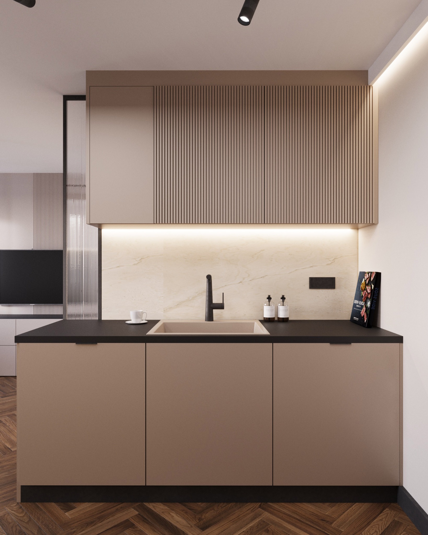 Nowoczesna kuchnia w odcieniach beżu i brązu z drewnianą podłogą w jodełkę, czarnym blatem, minimalistyczną armaturą i oświetleniem punktowym, z książką kucharską opartą o ścianę.
