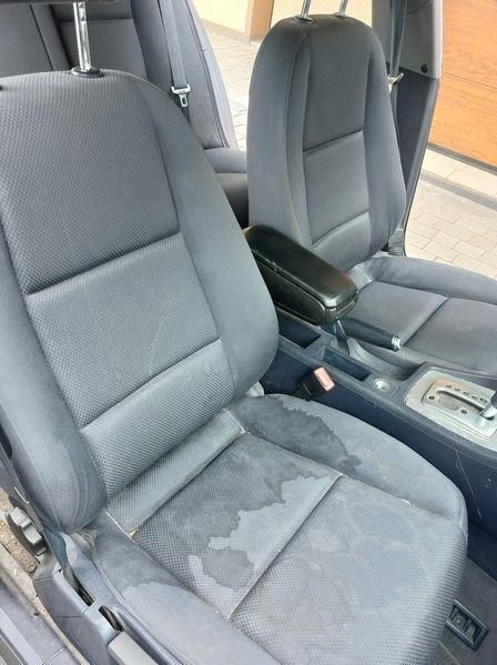 Szare, materiałowe fotele samochodowe z widocznymi plamami po czyszczeniu, ukazujące efekt przed i po.